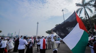 Massa aksi mengibarkan bendera Palestina saat Aksi Damai Bela Palestina di Monas, Jakarta, Minggu (5/11/2023). [Suara.com/Alfian Winanto]