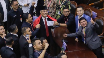 Ketua Majelis Kehormatan Mahkamah Konstitusi (MKMK) Jimly Asshiddiqie (tengah) dikalungi bendera merah putih oleh para pelapor usai sidang putusan etik di Gedung MK, Jakarta, Selasa (7/11/2023). [Suara.com/Alfian Winanto]