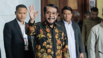 Mantan Ketua Mahkamah Konstitusi Anwar Usman menyapa awak media saat datang untuk memberikan keterangan pers di Gedung MK, Jakarta, Rabu (8/11/2023). [Suara.com/Alfian Winanto]