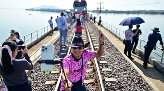 Seorang wisatawan berswafoto saat menaiki wisata "Kereta Apung" yang tengah berhenti di Bendungan Pasak Jolasid, Provinsi Lopburi, Thailand, Sabtu (4/11/2023). [MANAN VATSYAYANA / AFP]