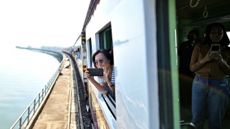 Seorang wisatawan mengabadikan pemandangan saat menaiki wisata "Kereta Apung" yang tengan melintas di Bendungan Pasak Jolasid, Provinsi Lopburi, Thailand, Sabtu (4/11/2023). [MANAN VATSYAYANA / AFP]