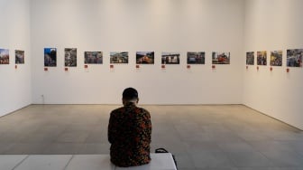 Pengunjung melihat karya yang dipamerkan di Pameran Foto Rekam Jakarta 2023 Masa ke Massa di Galeri Emiria Soenassa, Taman Ismail Marzuki (TIM), Jakarta, Selasa (21/11/2023). [Suara.com/Alfian Winanto]