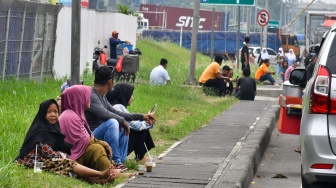 Sejumlah warga yang terdampak penutupan jalan di kawasan Industri MM 2100 beristirahat di trotoar saat buruh melakukan aksi di Kabupaten Bekasi, Jawa Barat,(23/11/2023). [ANTARA FOTO/ Fakhri Hermansyah/tom]