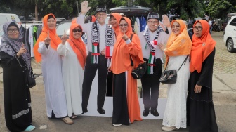 Pendukung berswafoto dengan figura Capres dan Cawapres nomor urut 1 Anies Baswedan dan Muhaimin Iskandar saat menghadiri kampanye perdana di GOR Ciracas, Jakarta, Selasa (28/11/2023). [Suara.com/Alfian Winanto]