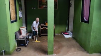 Warga membersihkan lumpur saat banjir melanda di kawasan Kebon Pala, Kampung Melayu, Jakarta, Kamis (30/11/2023). [Suara.com/Alfian Winanto]