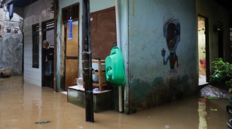 Warga beristirahat di rumahnya yang tergenang banjir di kawasan Kebon Pala, Kampung Melayu, Jakarta, Kamis (30/11/2023). [Suara.com/Alfian Winanto]