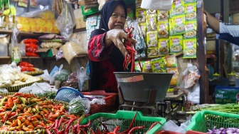 Pedagang menata cabai rawit dagangannya di pasar Cibubur, Jakarta, Kamis (7/12/2023). [Suara.com/Alfian Winanto]