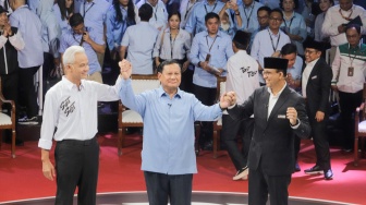 Capres nomor urut satu Anies Baswedan (kanan), Capres nomor urut dua Prabowo Subianto (tengah), Capres nomor urut tiga Ganjar Pranowo (kiri) saling berpegangan tangan usai debat perdana Capres dan Cawapres 2024 di Gedung KPU, Jakarta, Selasa (12/12/2023). [Suara.com/Alfian Winanto]