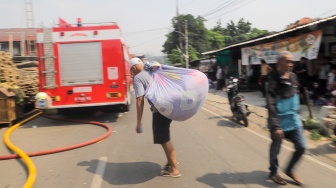 Warga mengevakuasi barang berharga saat kebakaran membakar pekukiman padat di kawasan Manggarai, Tebet, Jakarta, Kamis (14/12/2023). [Suara.com/Alfian Winanto]