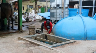 Pekerja memeriksa instalasi keran kontrol pada tangki biogas yang berasal dari limbah kotoran ternak di kawasan Pancoran, Jakarta, Jumat (15/12/2023). [Suara.com/Alfian Winanto]