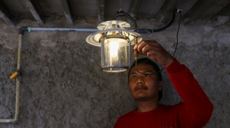 Pekerja menyalakan lampu yang menggunakan energi dari limbah kotoran ternak di kawasan Pancoran, Jakarta, Jumat (15/12/2023). [Suara.com/Alfian Winanto]