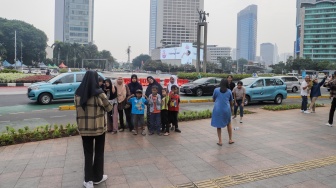 Warga berswafoto saat berwisata di Kawasan Bundaran HI, Jakarta, Senin (25/12/2023). [Suara.com/Alfian Winanto]