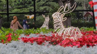 Sejumlah warga menghabiskan waktu liburan dengan bermain dan berfoto di depan dekorasi khas Natal di Taman Lapangan Banteng, Jakarta, Selasa (26/12/2023). [Suara.com/Alfian Winanto]