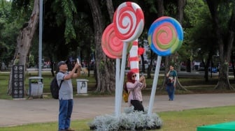 Sejumlah warga menghabiskan waktu liburan dengan bermain dan berfoto di depan dekorasi khas Natal di Taman Lapangan Banteng, Jakarta, Selasa (26/12/2023). [Suara.com/Alfian Winanto]