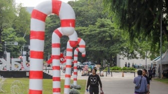 Sejumlah warga menghabiskan waktu liburan dengan bermain dan berfoto di depan dekorasi khas Natal di Taman Lapangan Banteng, Jakarta, Selasa (26/12/2023). [Suara.com/Alfian Winanto]