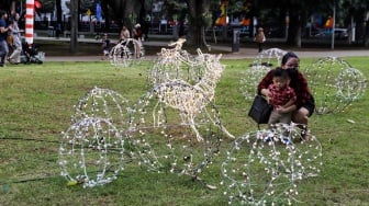 Sejumlah warga menghabiskan waktu liburan dengan bermain dan berfoto di depan dekorasi khas Natal di Taman Lapangan Banteng, Jakarta, Selasa (26/12/2023). [Suara.com/Alfian Winanto]