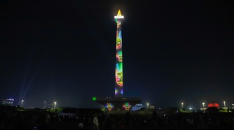 Pengunjung menyaksikan pertunjukan video mapping Monas Week di Monumen Nasional (Monas), Jakarta, Jumat (29/12/2023). [Suara.com/Alfian Winanto]