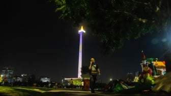 Pengunjung menyaksikan pertunjukan video mapping Monas Week di Monumen Nasional (Monas), Jakarta, Jumat (29/12/2023). [Suara.com/Alfian Winanto]