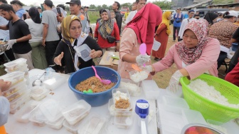 Warga membagikan makanan saat acara Masak Besar di Cilincing, Jakarta, Sabtu, (30/12/2023). [Suara.com/Alfian Winanto]