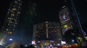 Warga melihat pertunjukan Drone Light Show dan Kembang Api saat Perayaan Tahun Baru 2024 di Bundaran HI, Jakarta, Senin (1/1/2024). [Suara.com/Alfian Winanto]
