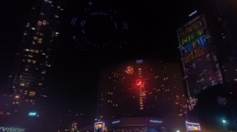 Warga melihat pertunjukan Drone Light Show dan Kembang Api saat Perayaan Tahun Baru 2024 di Bundaran HI, Jakarta, Senin (1/1/2024). [Suara.com/Alfian Winanto]
