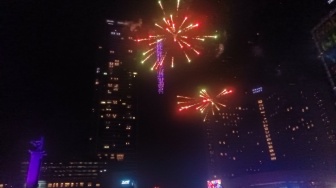 Warga melihat pertunjukan Drone Light Show dan Kembang Api saat Perayaan Tahun Baru 2024 di Bundaran HI, Jakarta, Senin (1/1/2024). [Suara.com/Alfian Winanto]