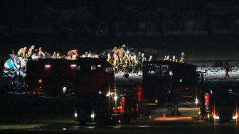 Kru penyelamat bekerja di lokasi pesawat Japan Airlines yang terbakar di landasan Bandara Haneda, Tokyo, Jepang, Selasa (2/1/2024). [Richard A. BROOKS / AFP]