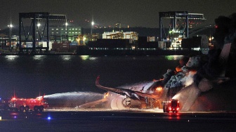 Petugas pemadam kebakaran berusaha memadamkan api di pesawat Japan Airlines yang terbakar di landasan Bandara Haneda, Tokyo, Jepang, Selasa (2/1/2024). [JIJI PRESS / AFP]