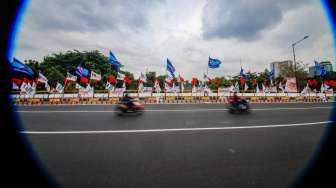 Warga melintas di samping alat peraga kampanye (APK) pemilu 2024 yang terpasang di pembatas jalur sepeda (stick cone) di kawasan Menteng, Jakarta, Selasa (9/1/2024). [Suara.com/Alfian Winanto]