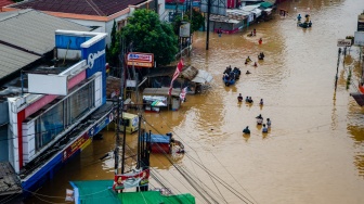 Warga berjalan melewati genangan banjir di Dayeuhkolot, Kabupaten Bandung, Jawa Barat, Jumat (12/1/2024). [Suara.com/Alfian Winanto]