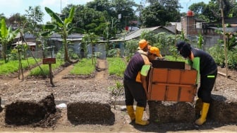 Petugas mengangkat alat cetak media tanam usai difermentasi di tempat penyaringan sampah di TB Simatupang, Jakarta, Jumat (12/1/2024). [Suara.com/Alfian Winanto]