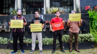 Aktivis dari Indonesia Corruption Watch (ICW)  menggelar aksi teaterikal menggunakan topeng Harun Masiku di depan gedung Merah Putih KPK, Jakarta, Senin (15/1/2024). [Suara.com/Alfian Winanto]