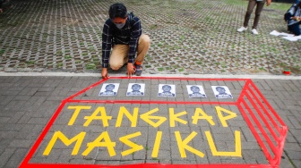 Aktivis dari Indonesia Corruption Watch (ICW) memasang selebaran bergambar Harun Masiku saat menggelar aksi teaterikal di depan gedung Merah Putih KPK, Jakarta, Senin (15/1/2024). [Suara.com/Alfian Winanto]