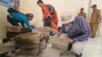 Arkeolog dari Balai Pelestarian Kebudayaan (BPK) wilayah XI Jawa Timur mengamati batu bata kuno yang diamankan di Balai Desa Kayunan, Kediri, Jawa Timur, Senin (15/1/2024). [ANTARA FOTO/Prasetia Fauzani/rwa]