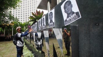 Aktivis dari Indonesia Corruption Watch (ICW) memasang selebaran bergambar Harun Masiku saat menggelar aksi teaterikal di depan gedung Merah Putih KPK, Jakarta, Senin (15/1/2024). [Suara.com/Alfian Winanto]