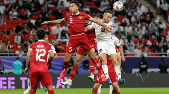 Gelandang Irak Osama Rashid menyundul bola melewati bek Indonesia Rizky Ridho saat pertandingan sepak bola Grup D Piala Asia 2023 antara Indonesia dan Irak di Stadion Ahmad bin Ali di Al-Rayyan, Doha, Qatar, Senin (15/1/2024). [KARIM JAAFAR / AFP]