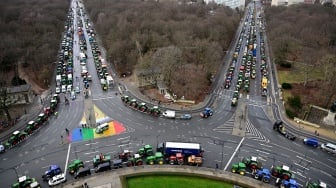 Traktor dan truk berbaris di dekat landmark gerbang Brandenburg saat berlangsungnya aksi protes para petani dan pengemudi truk di Berlin, Jerman, Senin (15/1/2024). [JOHN MACDOUGALL / AFP]