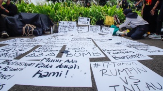 Aktivis memasang poster saat mengikuti aksi 17 Tahun Aksi Kamisan di depan Istana Negara, Jakarta, Kamis (18/1/2024). [Suara.com/Alfian Winanto]