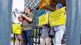 Aktivis dari Koalisi Pejalan Kaki menggelar aksi di Halte Tugu Tani, Jakarta, Senin (22/1/2024). [Suara.com/Alfian Winanto]