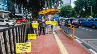 Aktivis dari Koalisi Pejalan Kaki menggelar aksi di Halte Tugu Tani, Jakarta, Senin (22/1/2024). [Suara.com/Alfian Winanto]