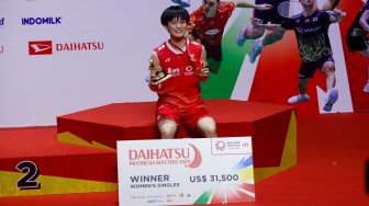 Pebulu tangkis Tunggal Putri Cina Wang Zhi Yi menunjukan medalinya usai menjuarai turnamen Indonesia Masters 2024 di Istora Senayan, Jakarta, Minggu (28/1/2024).  [Suara.com/Alfian Winanto]