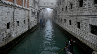 Seorang pengunjung mengenakan topeng dan kostum kuno berpose saat pra-pembukaan karnaval di Venesia, Italia, Sabtu (27/1/2024). [GABRIEL BOUYS / AFP] ​ 