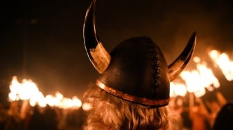 Seorang anggota Junior Up Helly Aa bereaksi ketika melihat sebuah kapal terbakar saat Festival Up Helly Aa di Lerwick, Kepulauan Shetland, Skotlandia, Selasa (30/1/2024). [ANDY BUCHANAN / AFP]