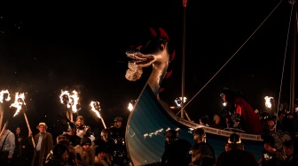 Anggota parade Up Helly Aa 'Jarl Squad' melintas sambil membawa obor saat Festival Up Helly Aa di Lerwick, Kepulauan Shetland, Skotlandia, Selasa (30/1/2024). [ANDY BUCHANAN / AFP] 
