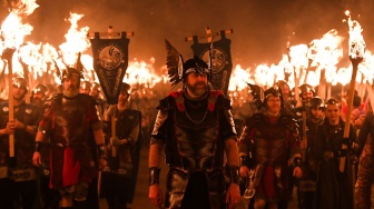 Anggota parade Up Helly Aa 'Jarl Squad' melintas sambil membawa obor saat Festival Up Helly Aa di Lerwick, Kepulauan Shetland, Skotlandia, Selasa (30/1/2024). [ANDY BUCHANAN / AFP]