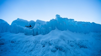 Orang-orang menjelajahi Ice Castles di North Woodstock, New Hampshire, Amerika Serikat, Kamis (1/2/2024). [Joseph Prezioso / AFP]