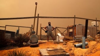 Seorang pria mengamati dampak kebakaran hutan yang melanda perbukitan di Quilpe comune, wilayah Valparaiso, Chili, Sabtu (3/2/2024). [Javier TORRES / AFP]