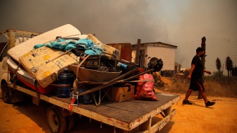 Sebuah truk mengangkut barang-barang saat terjadi kebakaran hutan di perbukitan di Quilpe comune, wilayah Valparaiso, Chili, Sabtu (3/2/2024). [Javier TORRES / AFP]