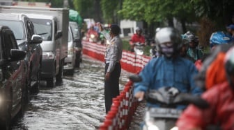 Kendaraan melintasi genangan banjir di Jalan DI Panjaitan, Jakarta, Senin (5/2/2024). [Suara.com/Alfian Winanto]