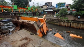 Warga melihat pos pantau Pintu Air Palmerah yang rubuh di Palmerah, Jakarta, Selasa (6/2/2024). [Suara.com/Alfian Winanto]